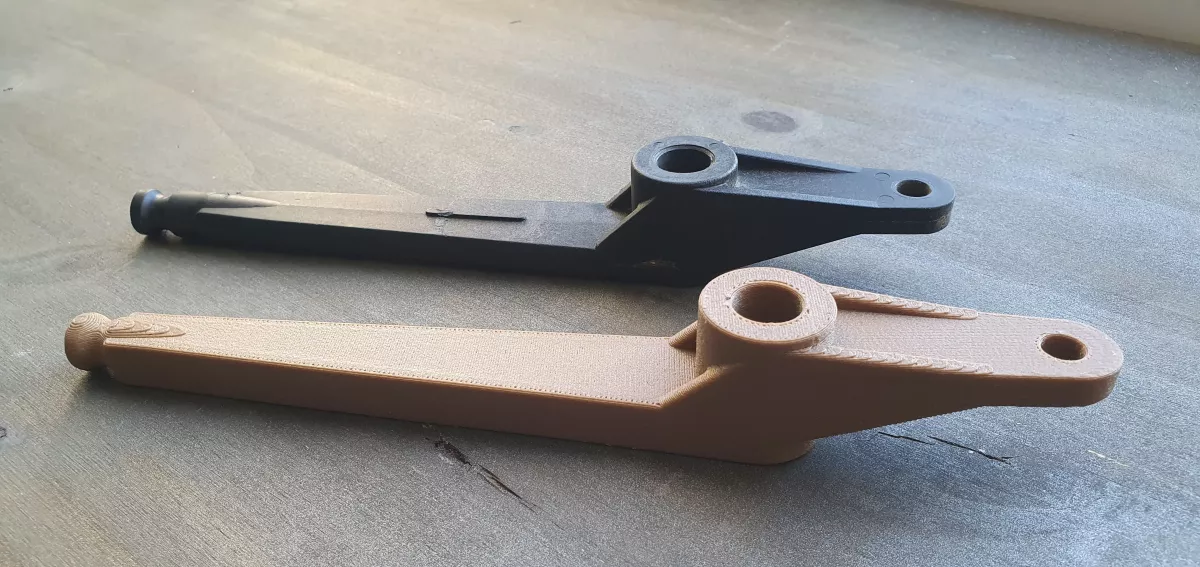 Comparaison entre une pièce mécanique originale noire et sa reproduction imprimée en 3D en PA6-GF (nylon fibre de verre), illustrant l'expertise en fabrication additive.